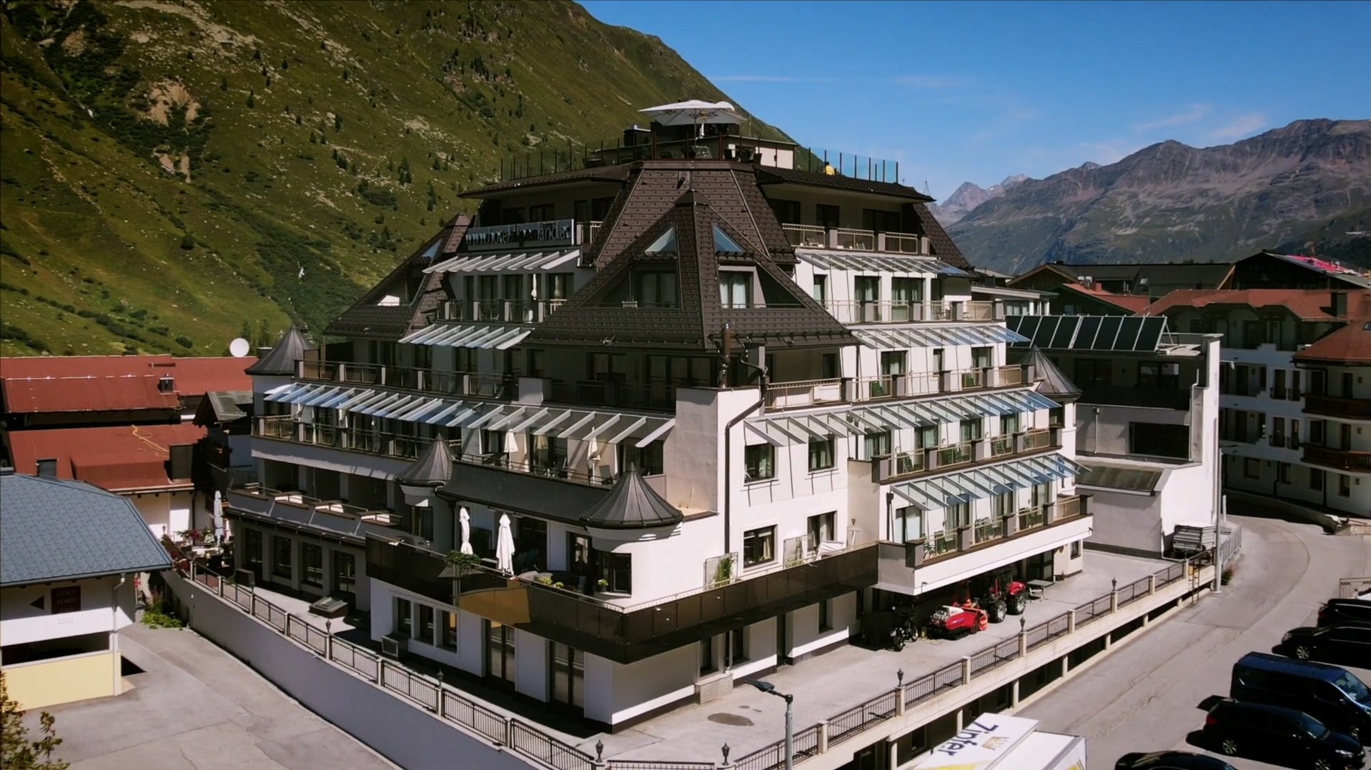 Einzigartige Architektur im Alpenland Großes Hotelgebäude in den Bergen mit mehreren Ebenen und Glaselementen, umgeben von Natur.