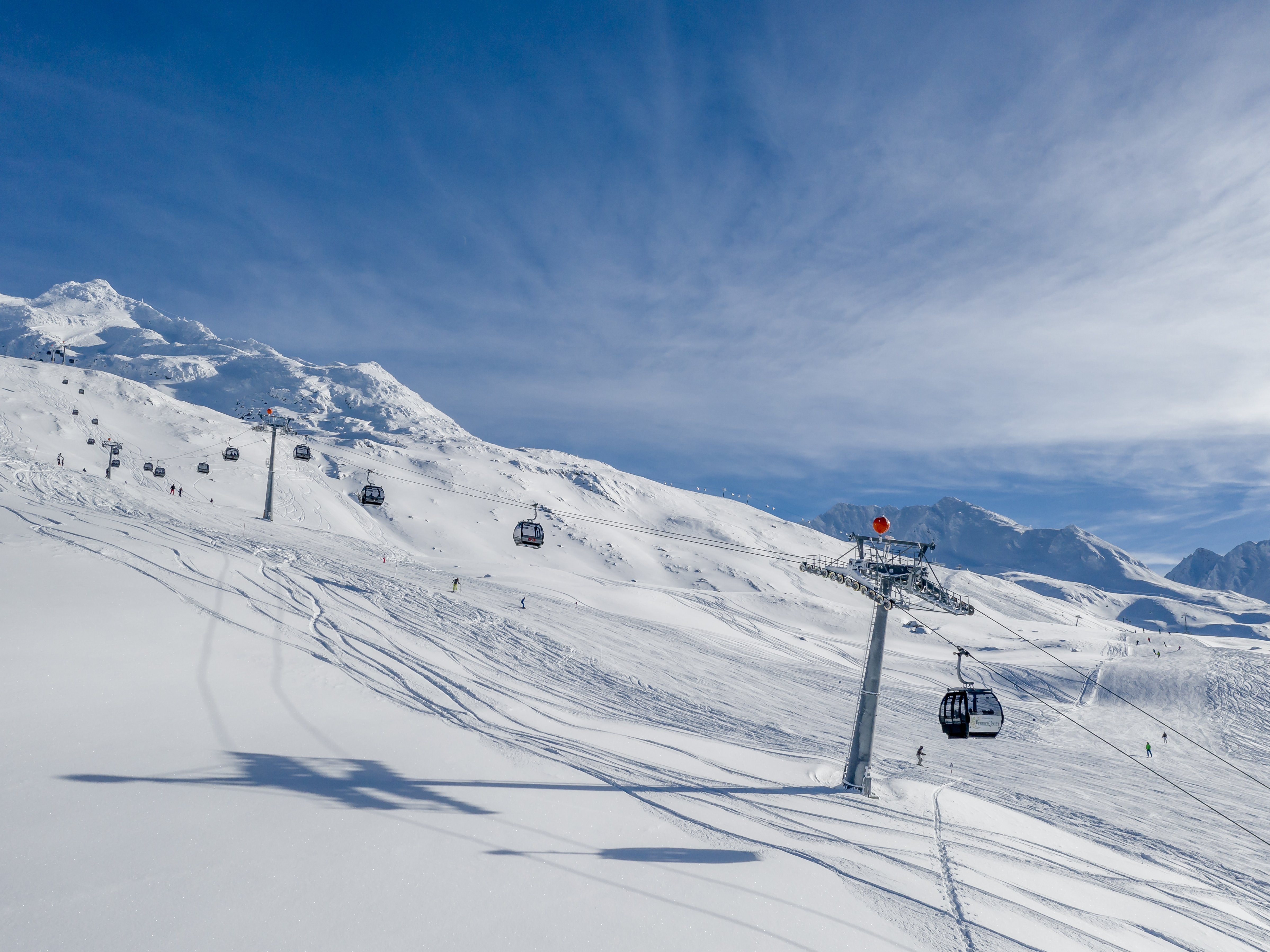 Schneebedeckte Berglandschaft im Winter Berglandschaft mit Schneedecke, Skiliften und Pisten im Vordergrund unter klarem Himmel.